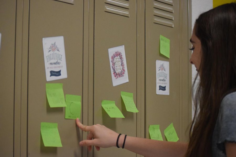 Eighth grader Keira Moran adds a positive post it note to a students locker during an activity to spread positivity. Photo by Andrew Brackett